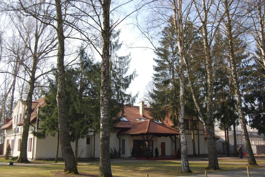 una casa blanca con árboles delante de ella en Hotel Restauracja Cztery Pory Roku en Orneta