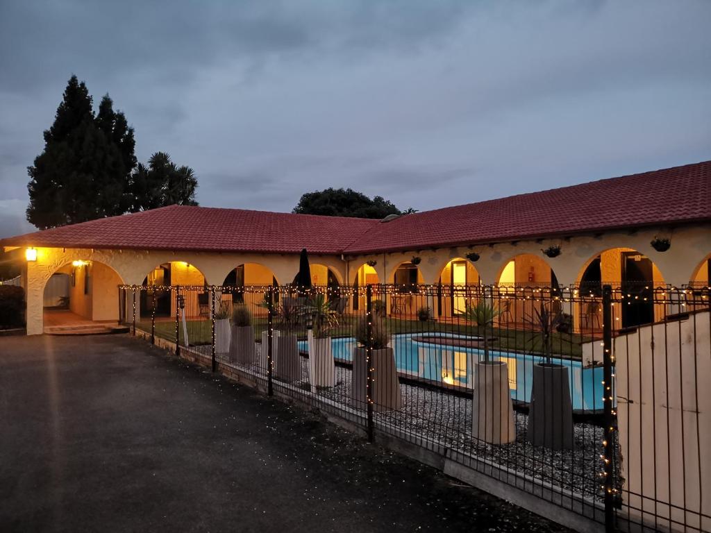 a building with a swimming pool and a fence at Captains Quarters Motor Inn in Cambridge