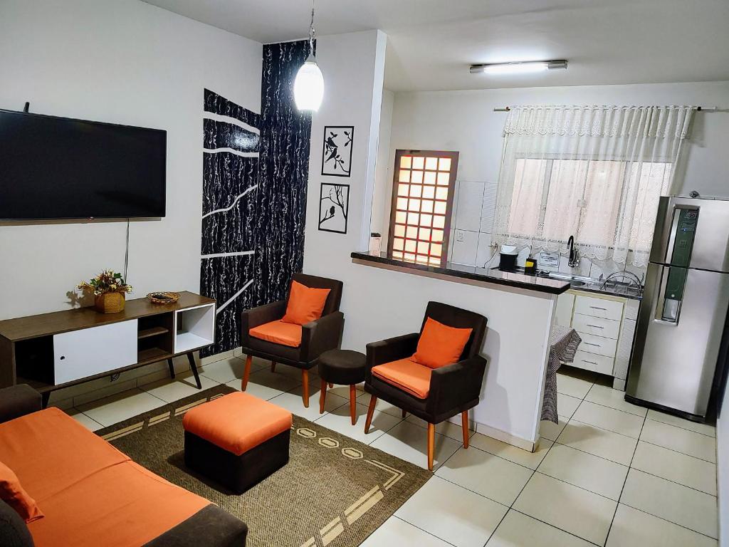 a living room with orange chairs and a kitchen at Casa Executiva Orla Morena in Campo Grande