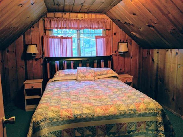 ein Schlafzimmer mit einem Bett in einem Zimmer mit Holzwänden in der Unterkunft Cabin #5 in Strawberry