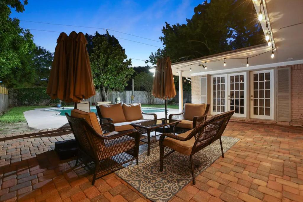 a patio with a table and chairs and umbrellas at Texas City Palace with 6 Beds and Private Pool in Texas City