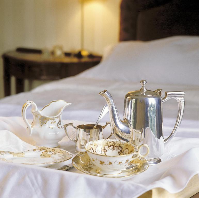 um bule de chá de prata e um conjunto de chá numa cama em Flemings Country House em Cork