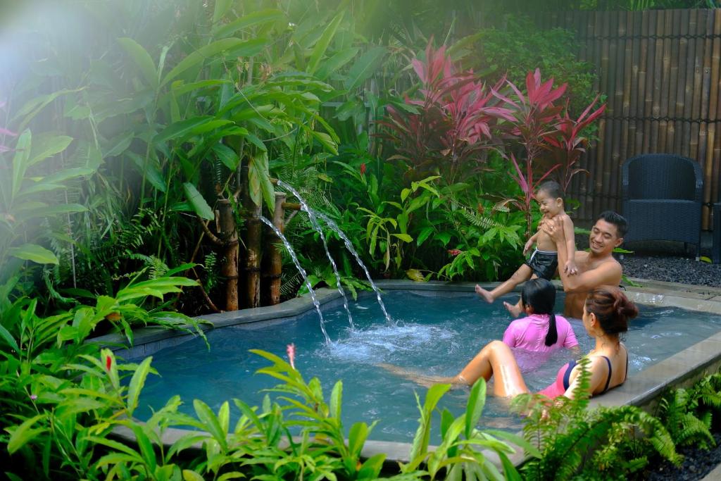 a group of people in a pool with a fountain at D'omah Yogya Hotel in Yogyakarta