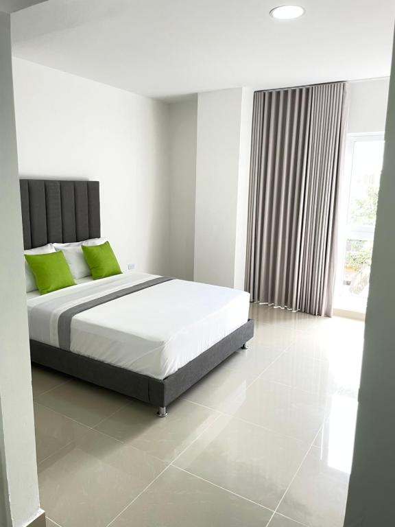 sypialnia z dużym łóżkiem z zielonymi poduszkami w obiekcie Apartaestudio en el peñón 304 w mieście Cali