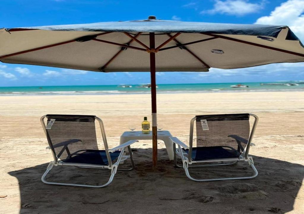 a table and chairs under an umbrella on the beach at Pousada La Riviera in Maragogi