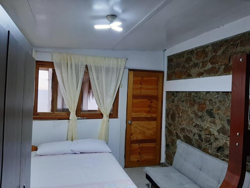 a bedroom with a bed and a window and a couch at Bungalows Bella Vista in Zorritos