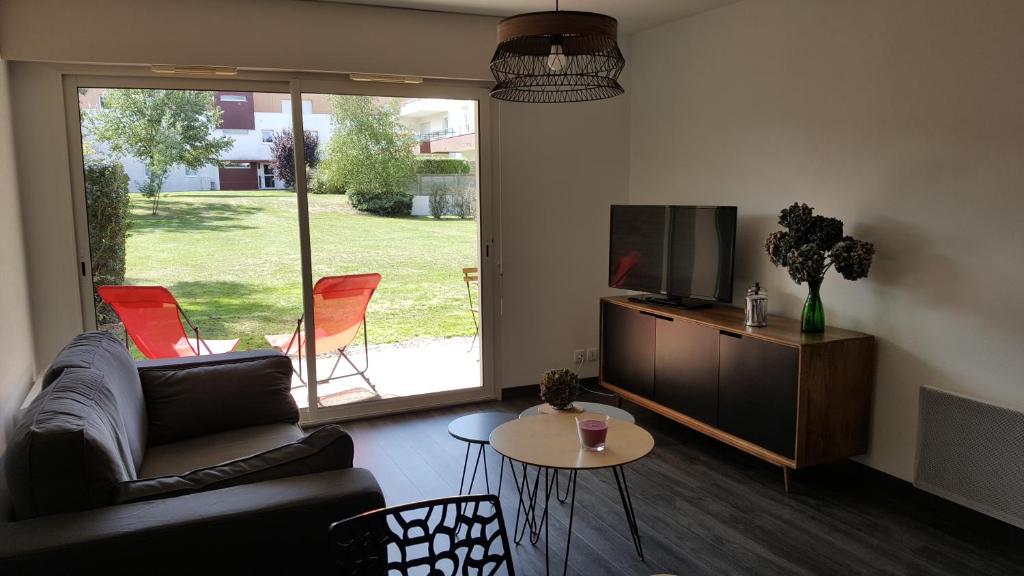 - un salon avec un canapé, une télévision et une table dans l'établissement Charmant Studio Résidence avec Terrasse Jardin au Centre de Vannes, à Vannes