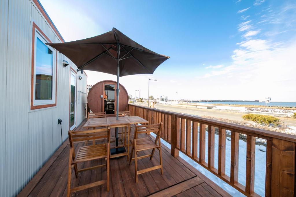 a wooden deck with a table and an umbrella at Okhotsk Ocean Villa AL MARE mombetsu in Mombetsu