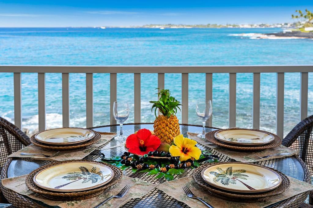 a table with plates and pineapple on the beach at Sea Village 1105 in Kailua-Kona