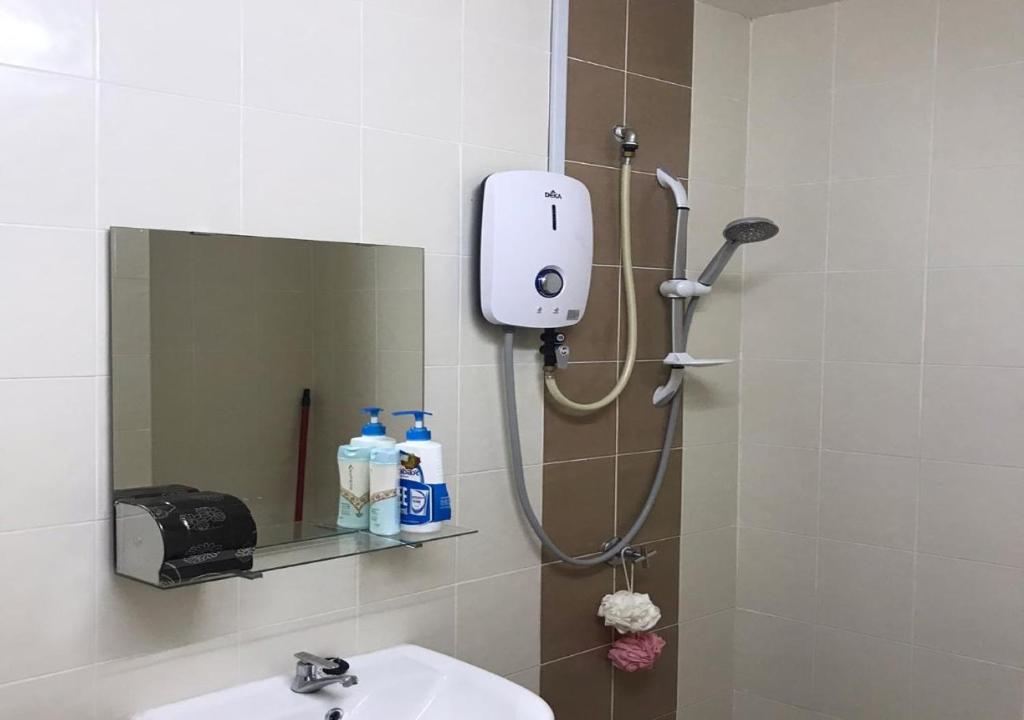 a shower in a bathroom with a sink and a mirror at Countryside Condo @One Residence Sekinchan in Sekincan