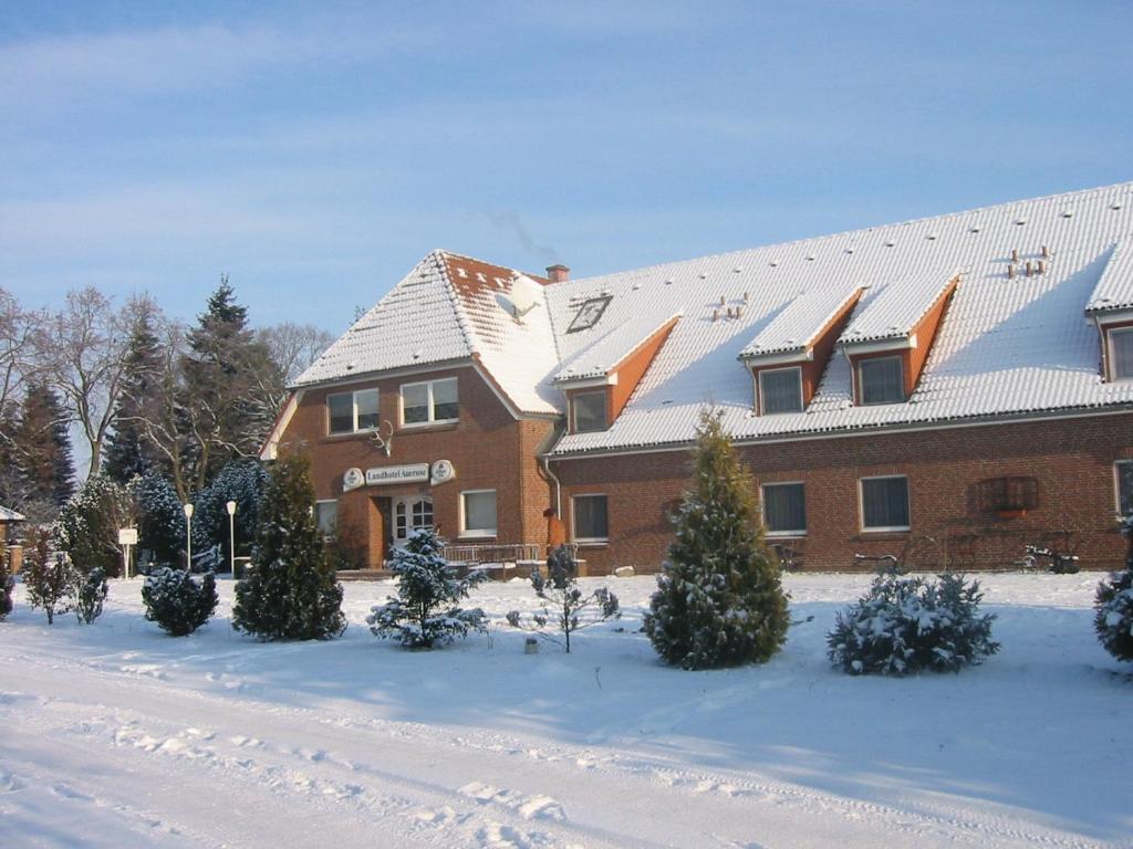 ein schneebedecktes Gebäude mit Bäumen davor in der Unterkunft Landhotel Auerose Garni in Neu Kosenow