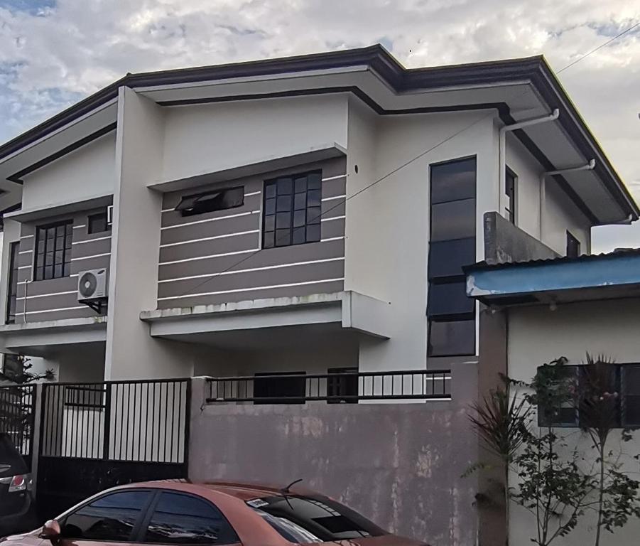 una casa blanca con un coche aparcado delante de ella en CHATEAU DE CHLOE - 3 Bedroom Entire Apartment for Large Group, en Tacloban