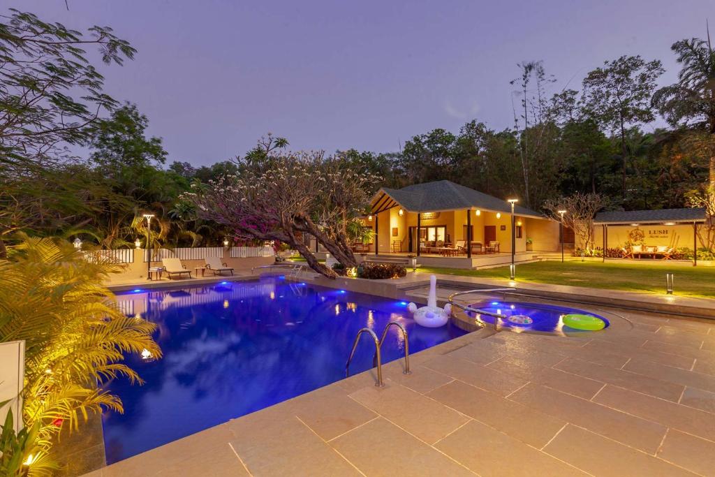 een huis met een zwembad in de nacht bij StayVista's Lush Villa - Lake-View Haven with Rustic-Meets-Modern Interiors, Pool, Jacuzzi & Indoor activities in Wādhiware