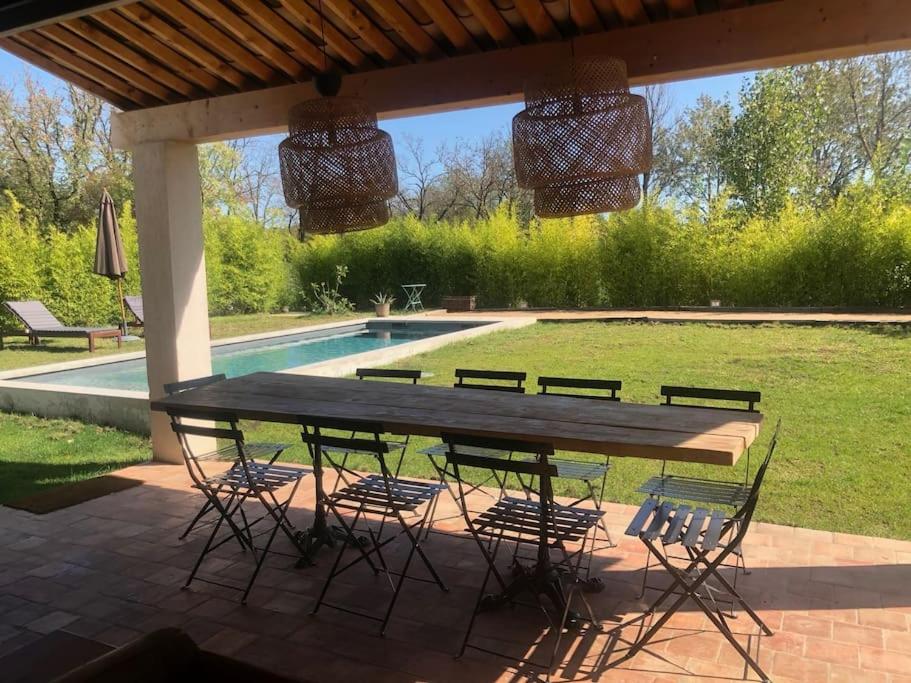 a picnic table and chairs under a pavilion with a pool at Villa neuve et moderne avec piscine à Grimaud in Grimaud