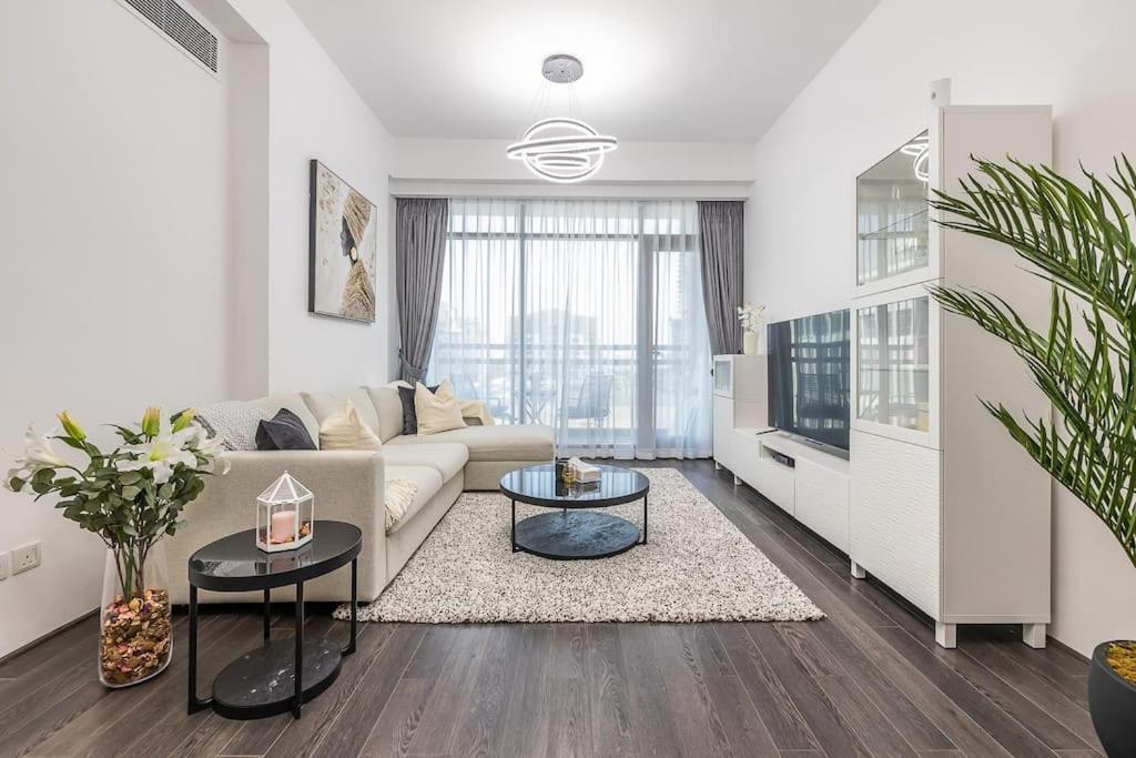 a white living room with a couch and a tv at Unique Cosy &Spacious 2BR In Al Sufouh in Dubai