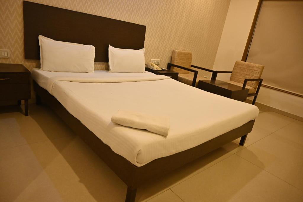 a bedroom with a large bed with white sheets and pillows at Regency Square Hotel in Gwalior