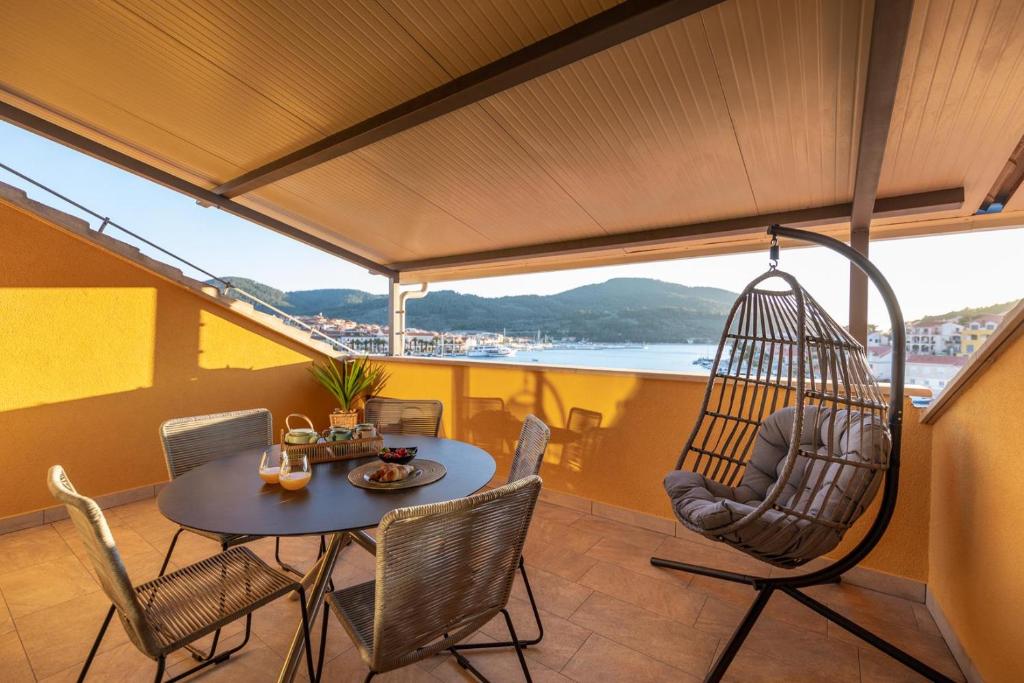 een balkon met een schommel, een tafel en stoelen bij PENTHOUSE J&A in Vela Luka