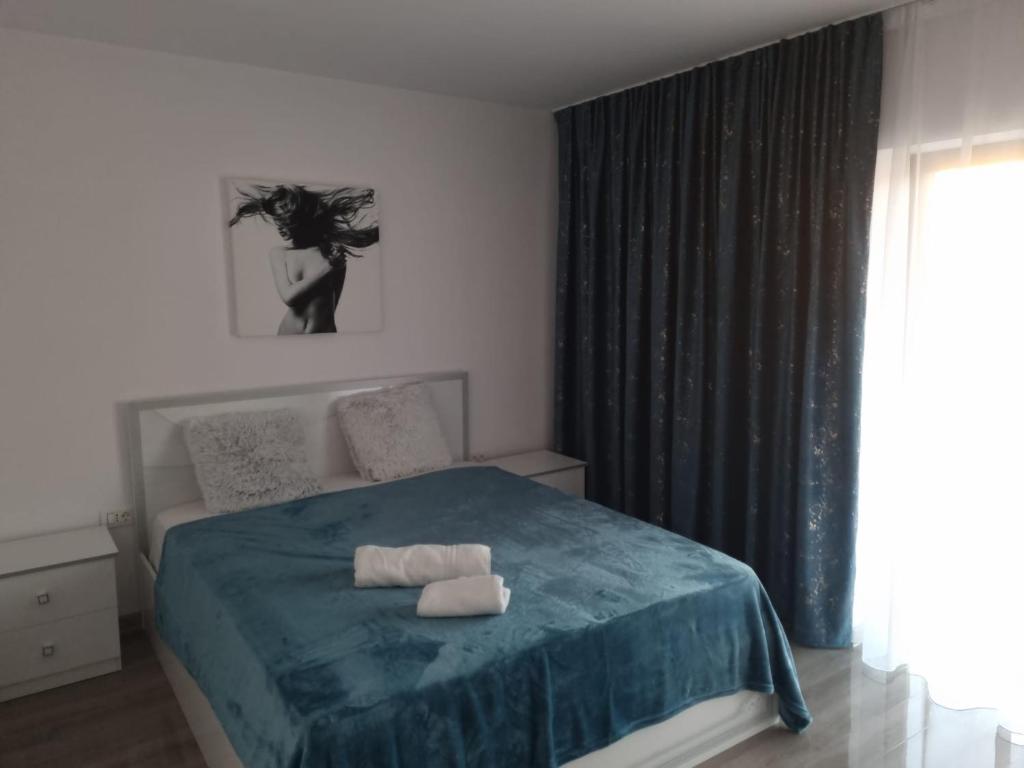 um quarto com uma cama com um cobertor azul e uma janela em Izabella Guest House em Săcele