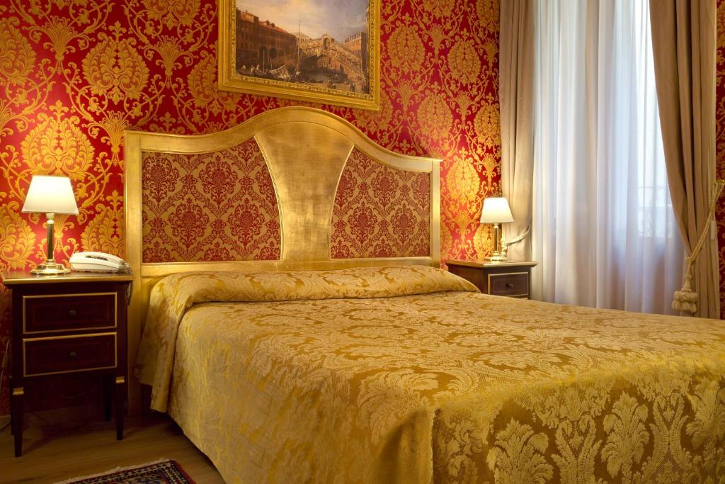 a bedroom with a bed and two night stands with lamps at Residenza Goldoni in Venice