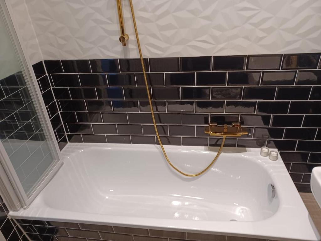 a bathroom with a bath tub with a gold shower at CITYLIFE Apartments Economy Osnabrück in Osnabrück