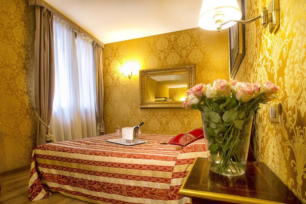 a room with a bed with a vase of flowers on a table at Residenza Goldoni in Venice