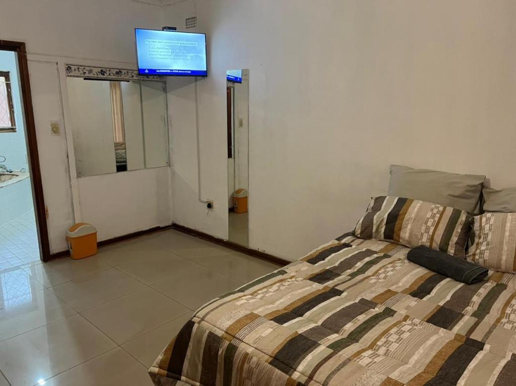 a bedroom with a bed and a tv on the wall at Empangeni guest house in Empangeni