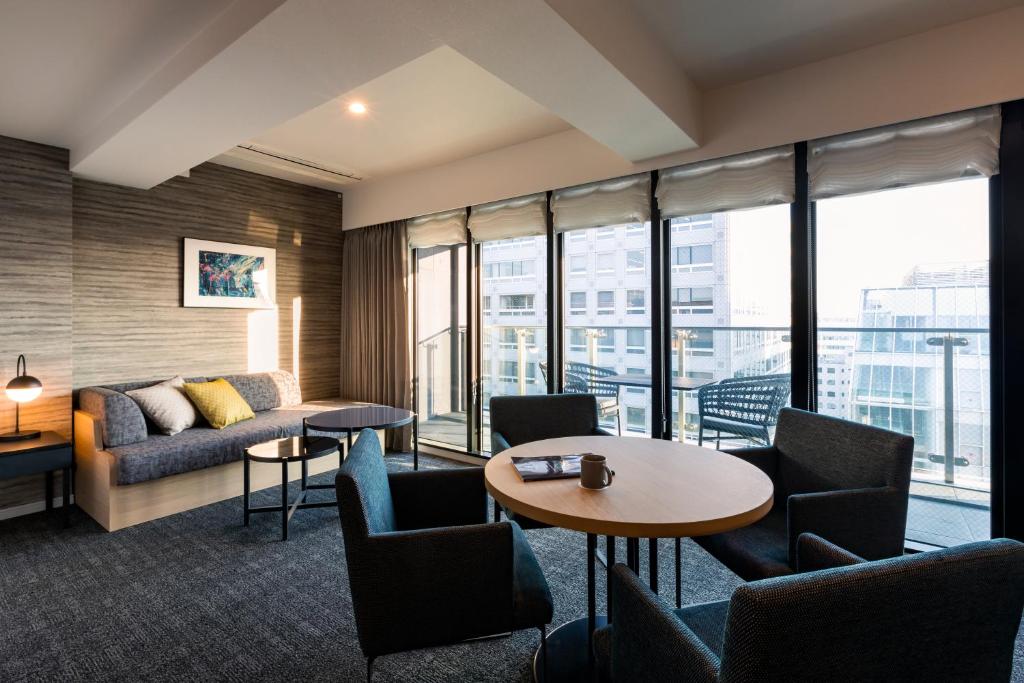 a hotel room with a couch and a table and chairs at Rinn Kyoto Station in Kyoto