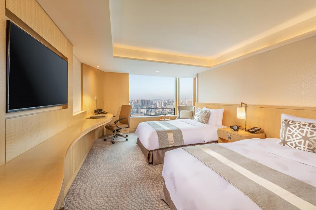 a hotel room with two beds and a flat screen tv at White Swan Hotel in Guangzhou