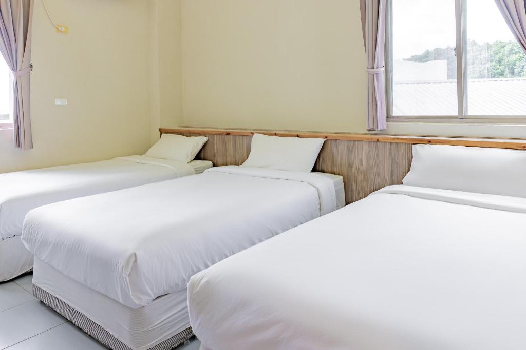 a row of three beds in a room with windows at Star-Moon B&amp;B Green Island in Green Island