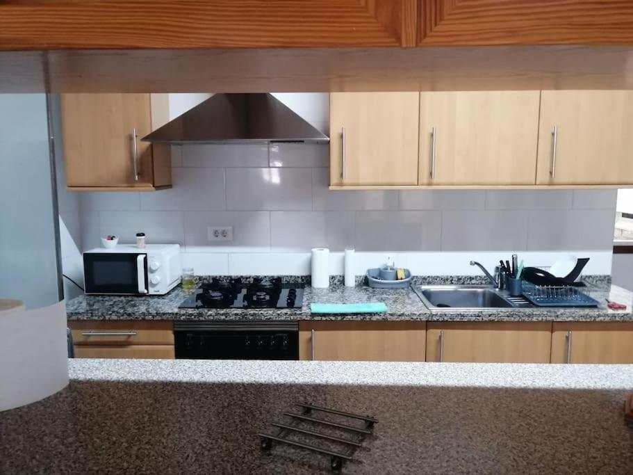 a kitchen with a stove and a sink and a microwave at Habitación matrimonial privada con areas compartidas in Las Lagunas