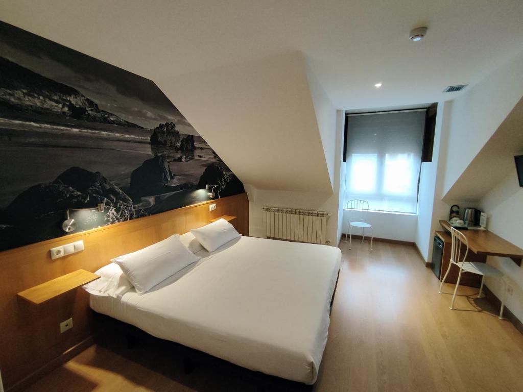 a bedroom with a large white bed and a desk at Hotel Dabeleira in Luarca