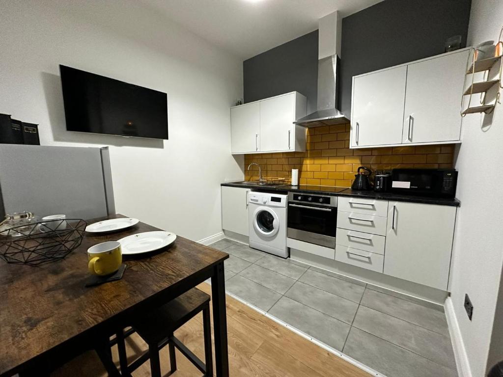 een keuken met witte kasten en een houten tafel bij Bee Accommodations in Leicester