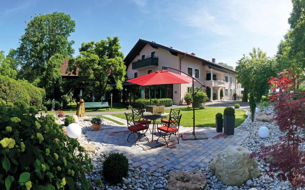 a patio with chairs and a table with a red umbrella at Landhaus Riedl in Bad Füssing