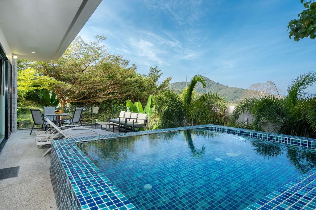 una piscina con dos sillas y una mesa en Villa Natural Touch A3, en Kamala Beach