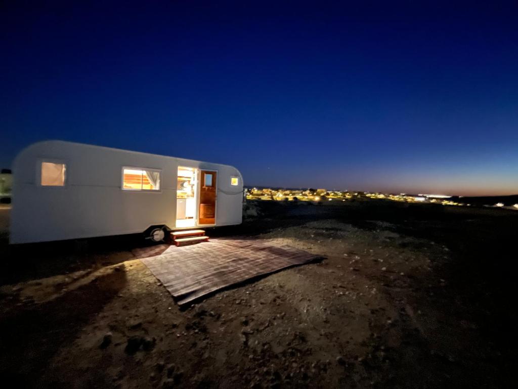a white trailer parked in a field at night at קסיופאה חוויה במדבר in Yeroẖam