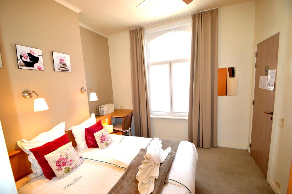 a bedroom with a bed with red pillows and a window at Hotel Ambrosia in Ieper