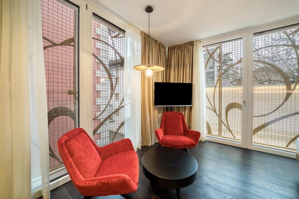 - un salon avec 2 chaises rouges et une télévision dans l'établissement Villa Steiner 5 - Suzuka, à Merano