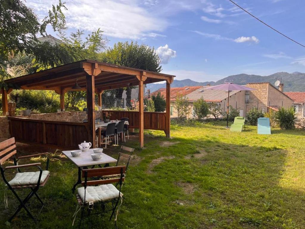 une table et des chaises sous un pavillon dans une cour dans l'établissement A Funtanella, maison de caractere situe entre montagne et mer, à Tavera
