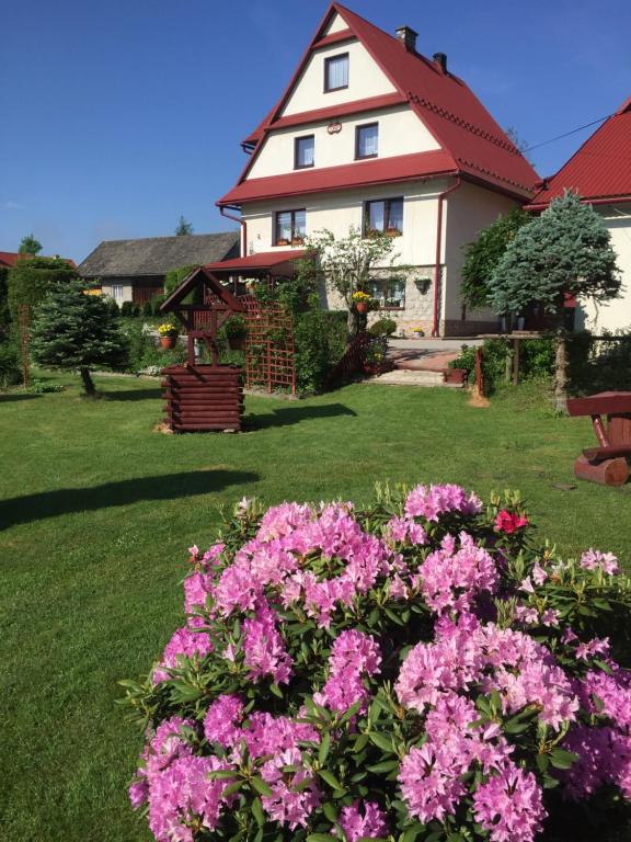 a house with pink flowers in front of a yard at Agroturystyka Pod Dzwonnicą in Zubrzyca Górna