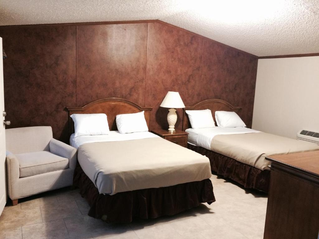una habitación de hotel con 2 camas y una silla en Oasis Lodge, en Big Lake
