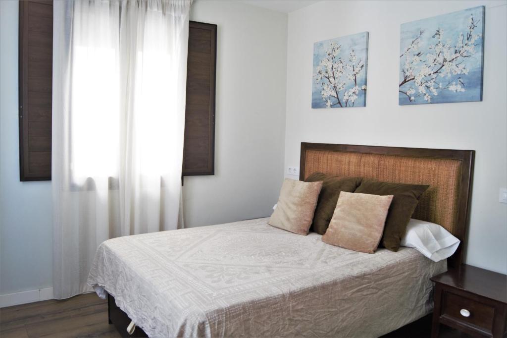 a bedroom with a bed with white sheets and a window at Home Sweet Home junto a Mezquita / Wifi / Parking in Córdoba