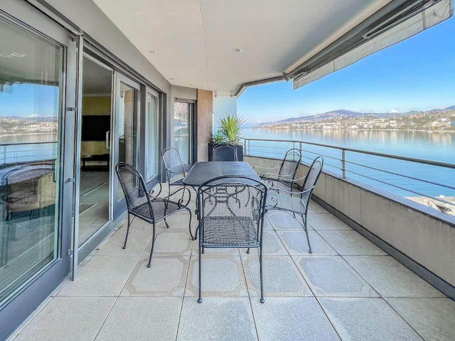 einen Tisch und Stühle auf einem Balkon mit Blick auf das Wasser in der Unterkunft Forum Luxury Apartment Lake View in Montreux