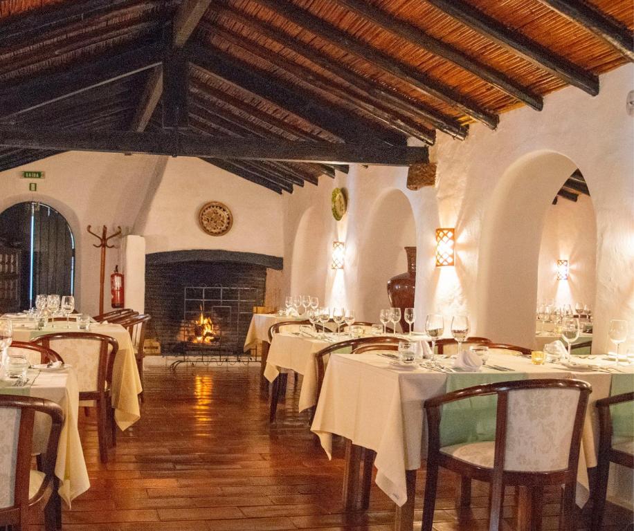 a dining room with white tables and chairs and a fireplace at Pedras D'el Rei in Tavira