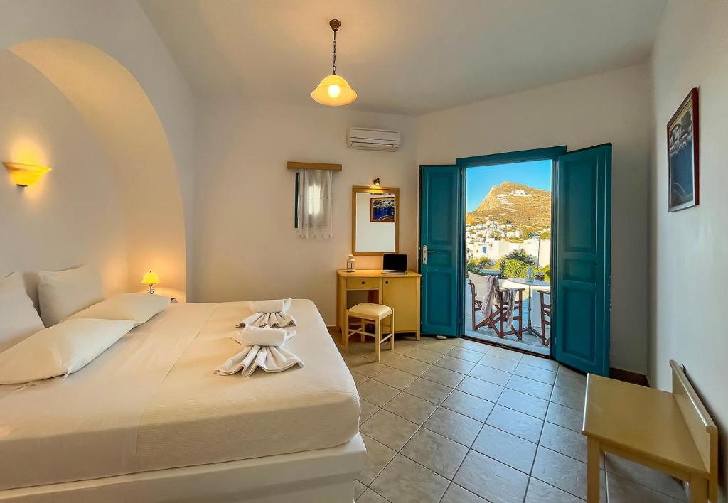 um quarto com uma cama e uma porta com uma varanda em Horizon Hotel em Chora Folegandros