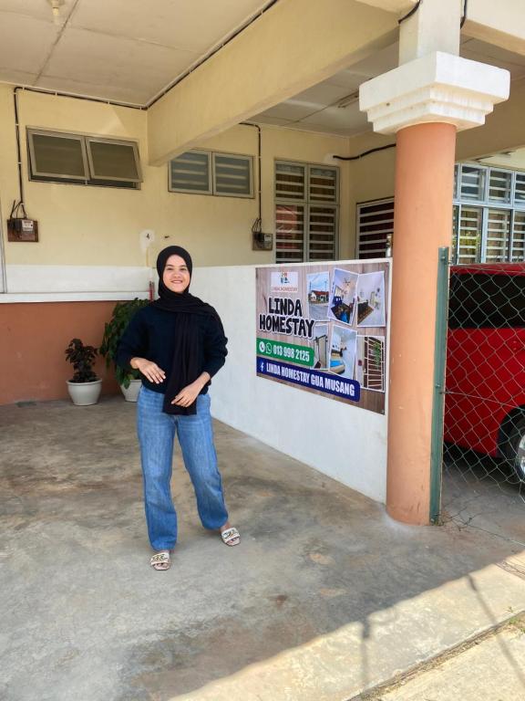 a woman is standing in front of a building at LH Homestay Bandar Utama Gua Musang in Gua Musang