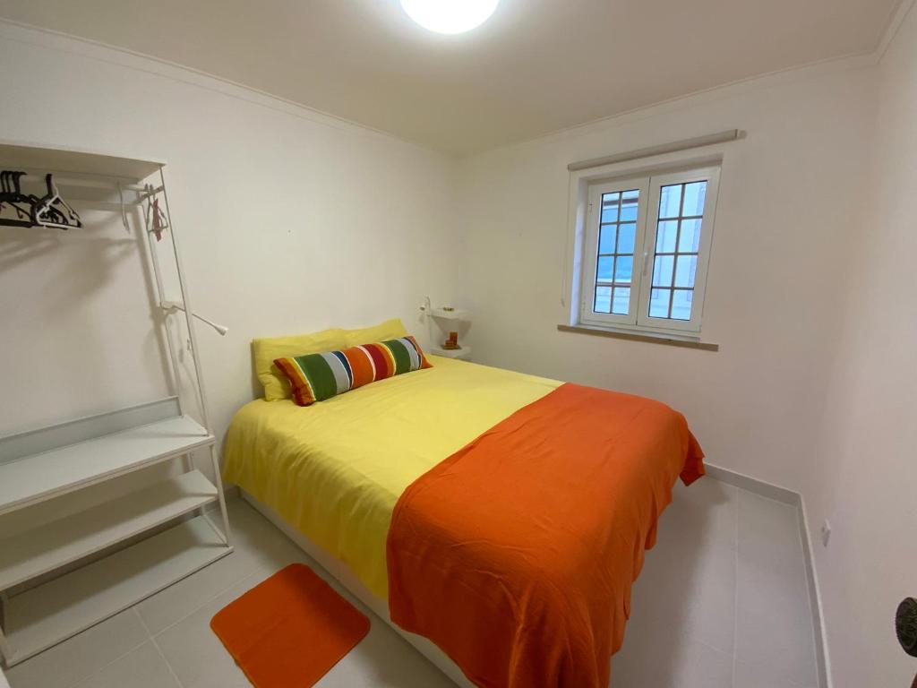 een slaapkamer met een bed met een oranje deken bij O Cabaça in Sesimbra