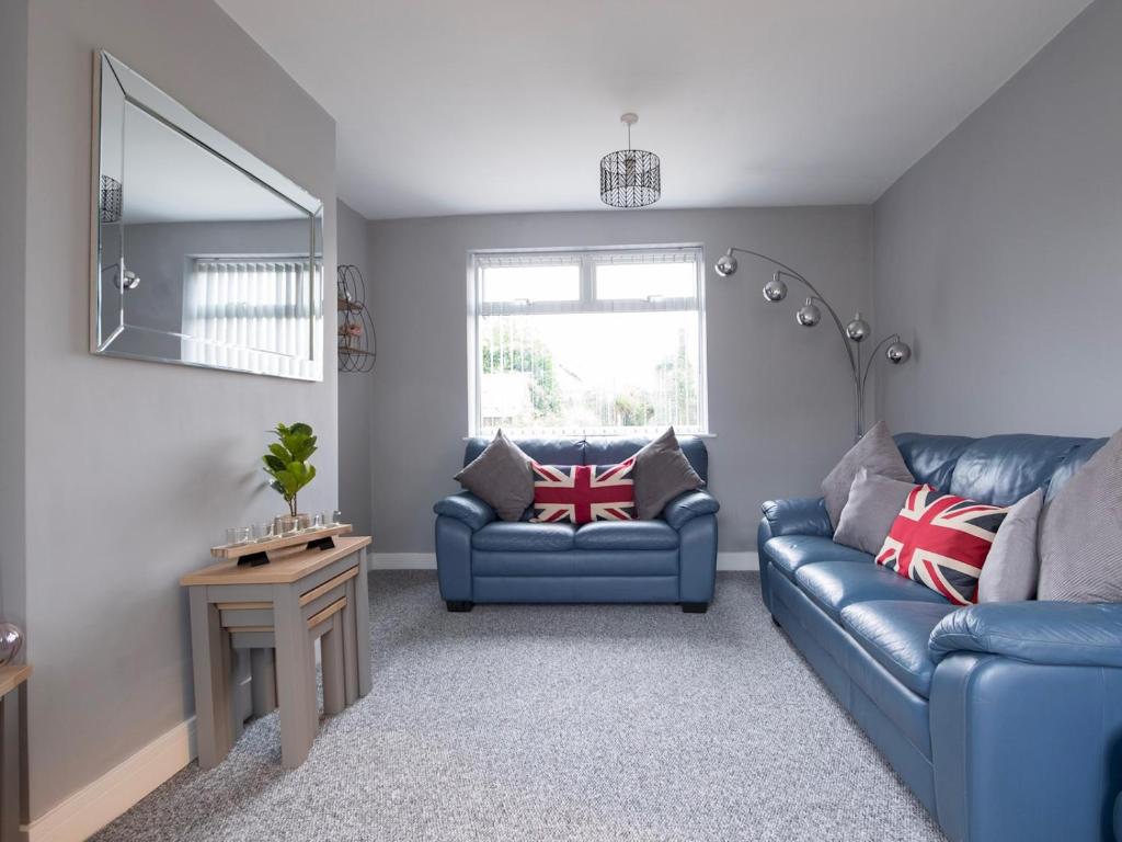 a living room with two blue couches and a mirror at Pass the Keys Spacious house with free parking in Doncaster