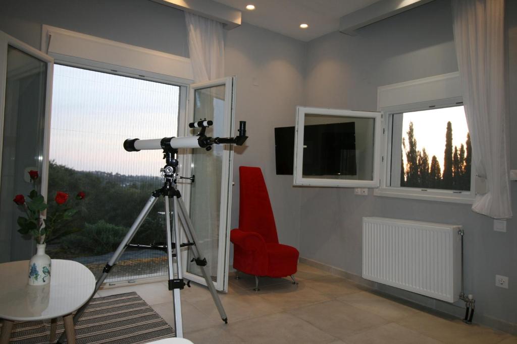 a room with a camera and a red chair and window at Corfu Luxury Apartment, Tranquility, Mountain & Sea Views in Agios Gordios