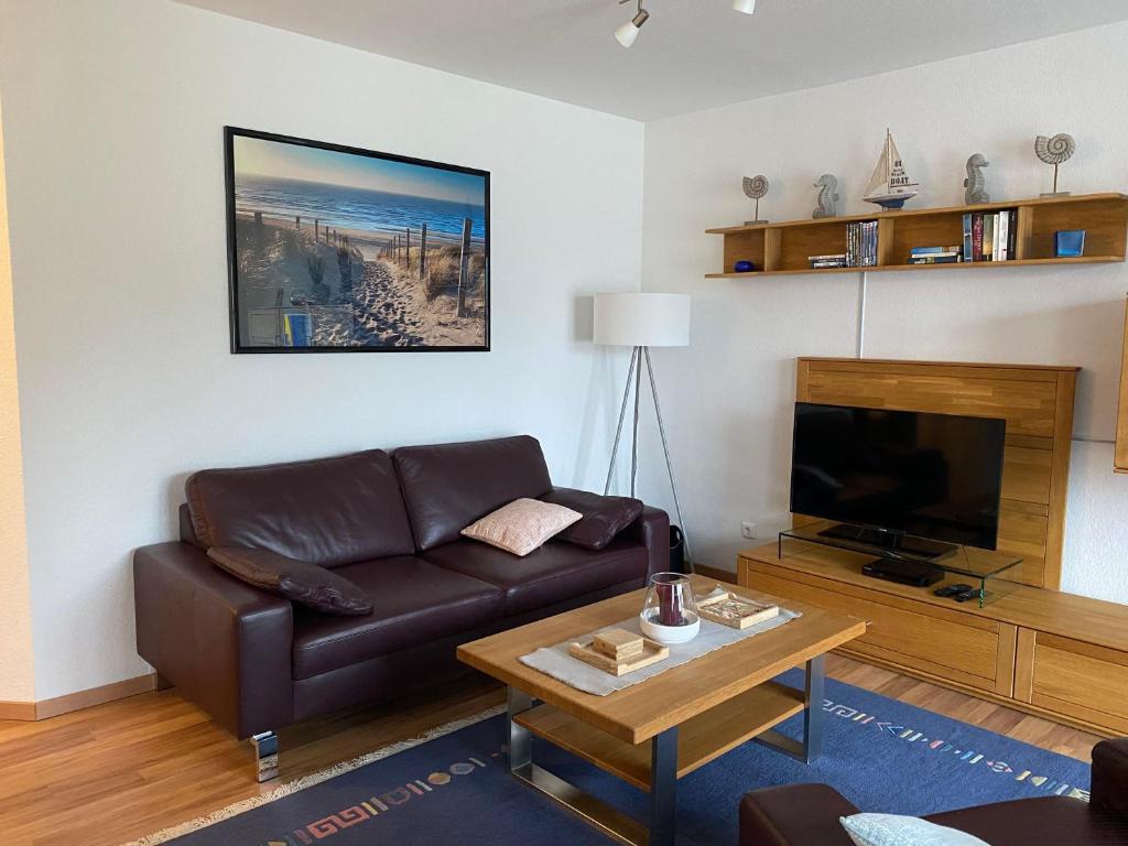 uma sala de estar com um sofá de couro castanho e uma televisão em Haus-Olymp-Apartement-01-Kuehlungsborn-nur-50-m-bis-zum-Strand-ca-50-m2-2-Raeume-sehr-gepflegt em Kühlungsborn