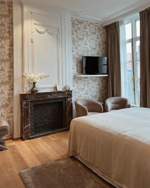 a bedroom with a bed and a fireplace and a tv at Hotel Van Cleef in Bruges